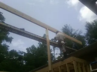 Carpenter setting a ridge beam over a new addition frame — Ice Dam Removal by Roofing Brothers in Burgaw