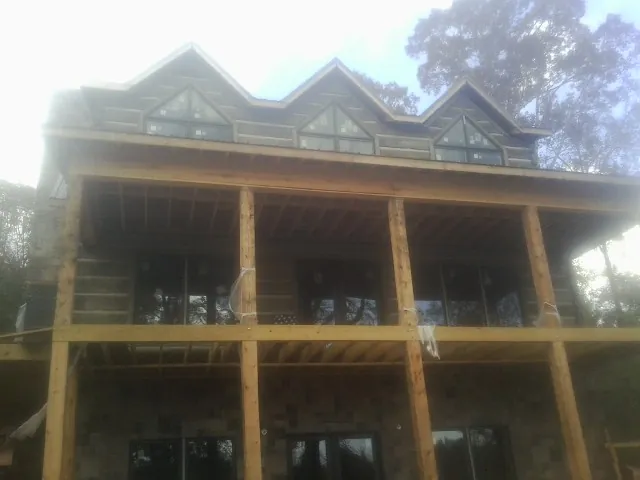 Dormers and porch framing on a large log home under construction — Roof Coating work by our crew in Burgaw