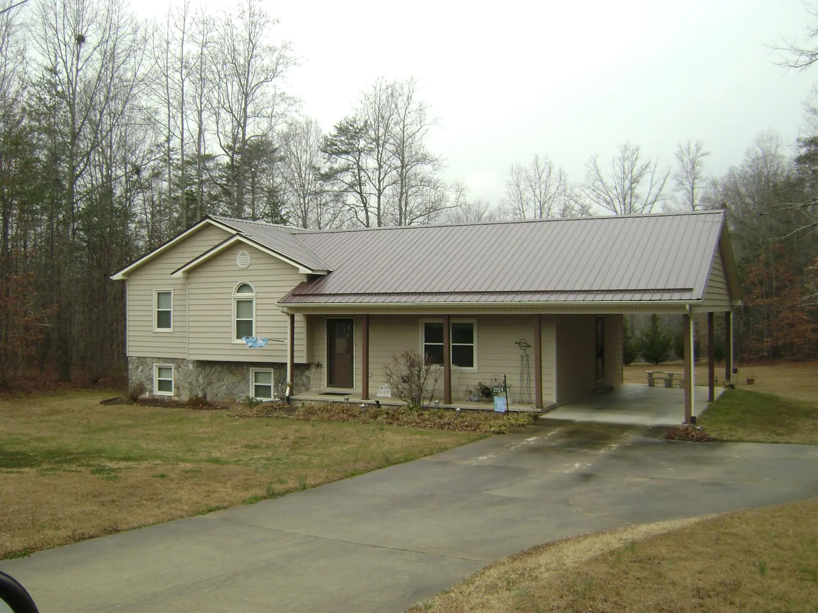 Brown metal roof on a tan split level home with an attached carport in Burgaw